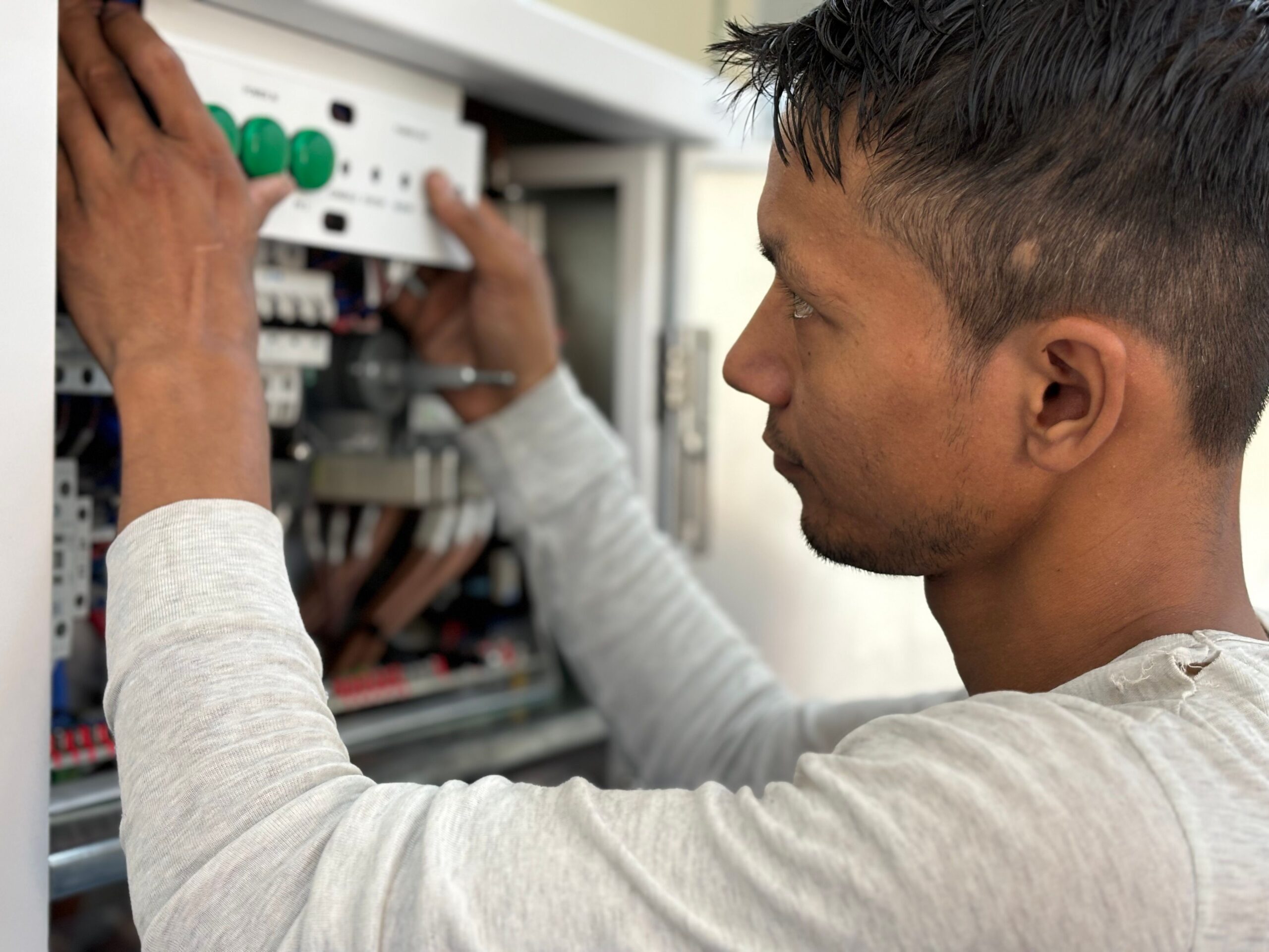 Électricien réglant un tableau électrique lors de travaux d'électricité à Plaisir
